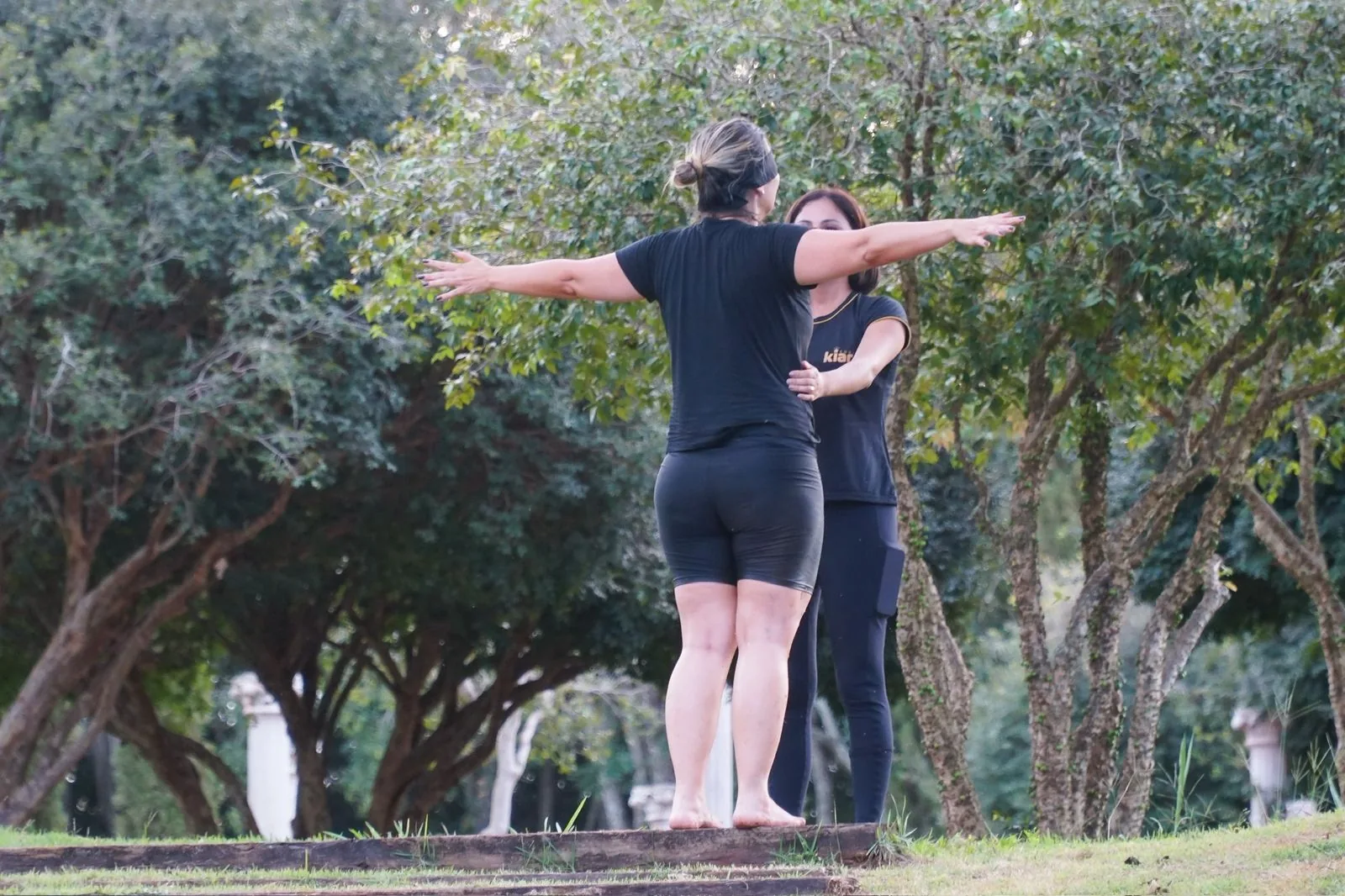 Duas mulheres de braços abertos em um parque