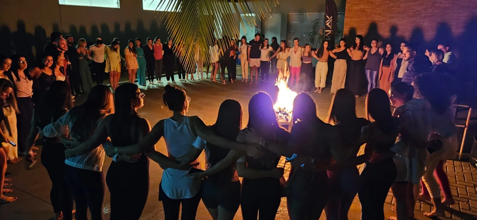 Roda de pessoas abraçadas em volta do fogo